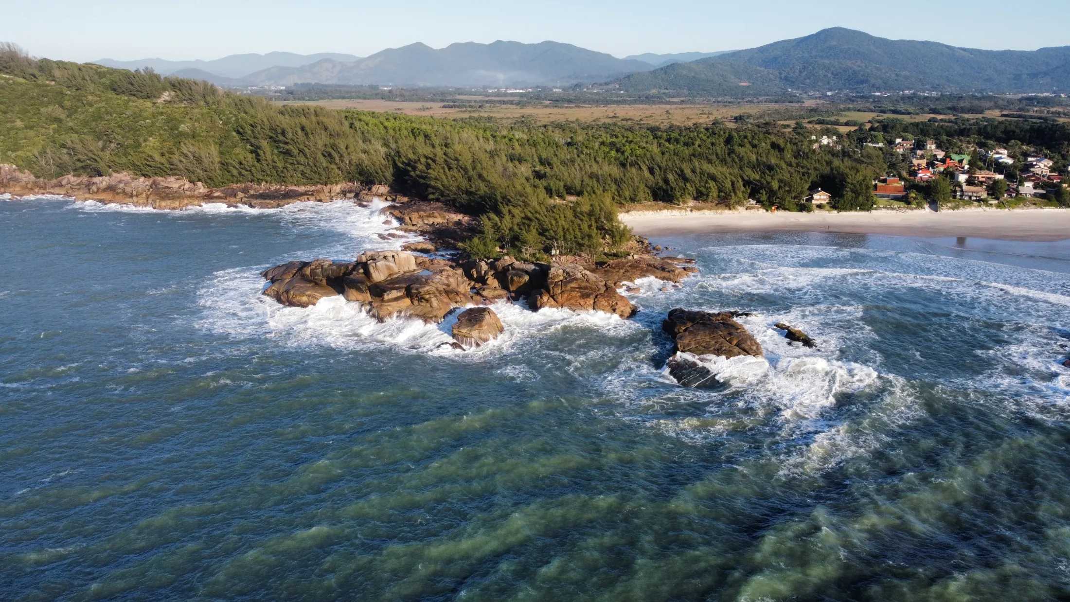 Costão rochoso com montanhas ao fundo